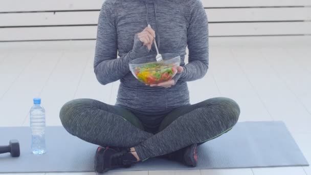 Концепция здорового питания. Молодая крепкая женщина ест здоровый салат после тренировки — стоковое видео