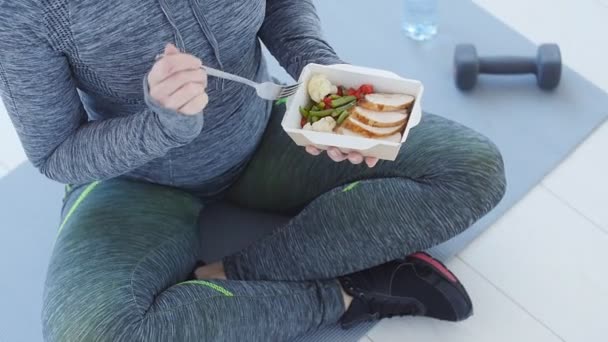 Concepto de deporte y alimentación saludable. Mujer joven y saludable comiendo pollo y verduras — Vídeos de Stock
