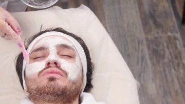 Erkekler için spa kavramı. Genç bir adam uygulanan kozmetik güzellik salonu yüzüne maske