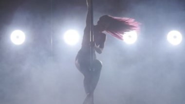 Duman ve arka ışık ile karanlık bir odada dans kutup genç kadın