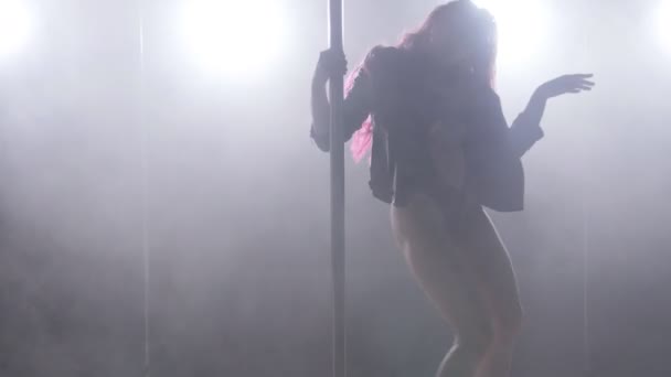 Jeune femme sur un poteau dansant dans une pièce sombre avec rétro-éclairage et fumée — Video
