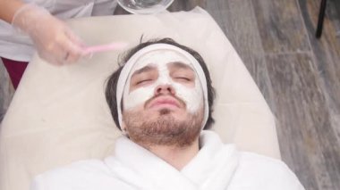 Kozmetik ve spa hizmetleri kavramı. Genç adam kil maskesi güzellik Spa ile