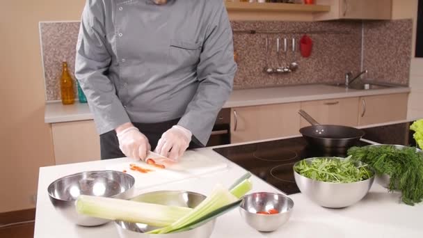 Koken concept. Jonge man snijdt de groenten in de keuken — Stockvideo