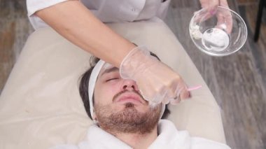 Kozmetik ve spa hizmetleri kavramı. Genç adam kil maskesi güzellik Spa ile