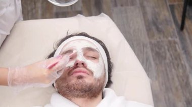 Kozmetik ve spa hizmetleri kavramı. Genç adam kil maskesi güzellik Spa ile