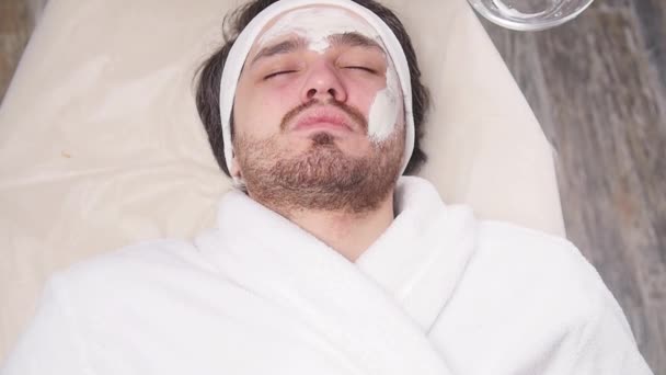 Pojęcie usług kosmetycznych i spa. Młody człowiek z gliny maseczka na twarz w spa — Wideo stockowe