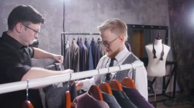 Alışveriş kavramı. Satıcı genç bir adam bir takım elbise içinde belgili tanımlık stok seçmek için yardımcı olur.