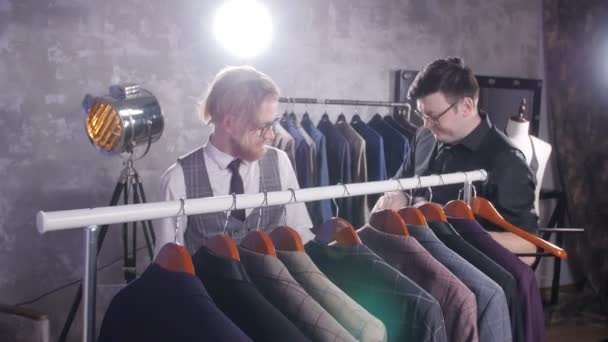 Concepto de compras. Vendedor ayuda a un joven a elegir un traje en la tienda — Vídeos de Stock
