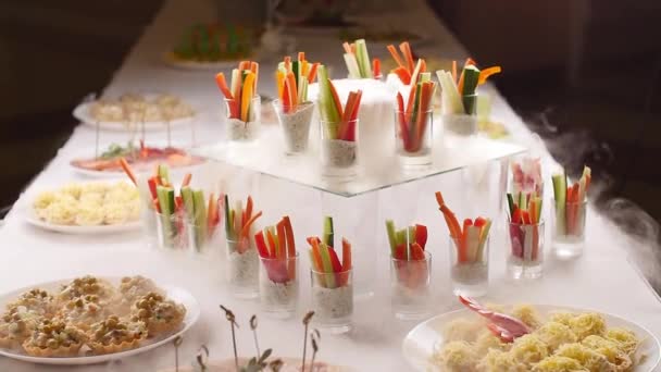 Concepto de comida en una fiesta. Sabrosos aperitivos servidos en frascos de vidrio con humo de hielo frito en la mesa — Vídeo de stock