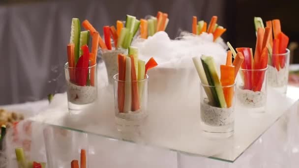 Concept of food at a party. Tasty appetizers served in glass jars with fry ice smoke on table — Stock Video