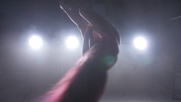 Begreppet dans och akrobatik. Ung smal kvinna pole dance i mörka interiören med bakgrundsbelysning och rök — Stockvideo