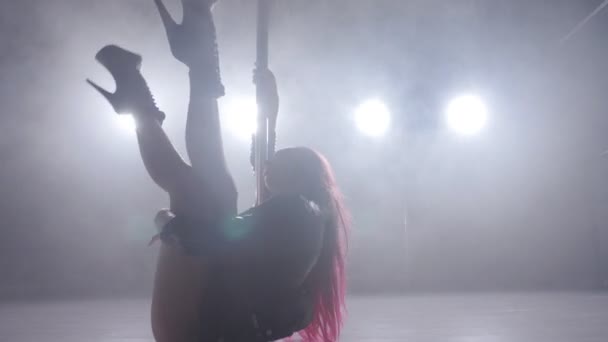 Begreppet dans och akrobatik. Ung smal kvinna pole dance i mörka interiören med bakgrundsbelysning och rök — Stockvideo