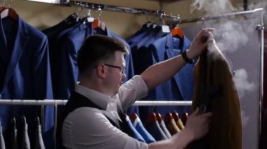 Adam satıcı kostüm dükkanında onu Satılık hazırlanması onun ceketini çıkar, şeritler.