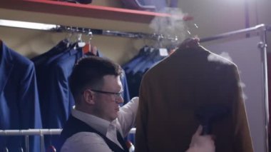 Adam satıcı kostüm dükkanında onu Satılık hazırlanması onun ceketini çıkar, şeritler.