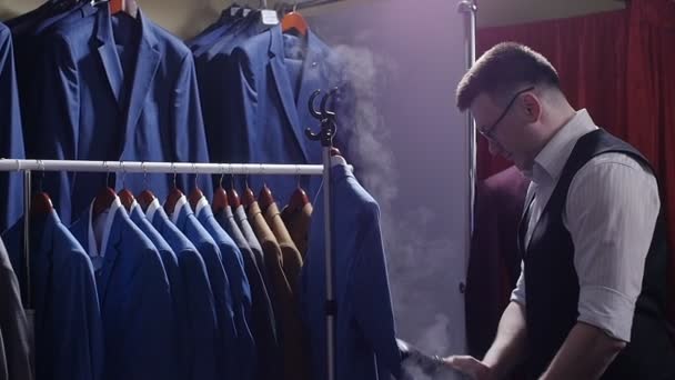 Człowiek sprzedawca w sklepie kostium prążki poza jego kurtka, przygotowując go do sprzedaży. — Wideo stockowe