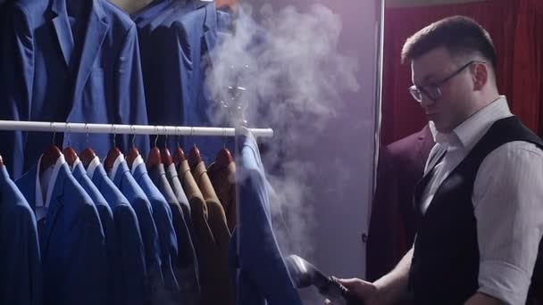 Człowiek sprzedawca w sklepie kostium prążki poza jego kurtka, przygotowując go do sprzedaży. — Wideo stockowe