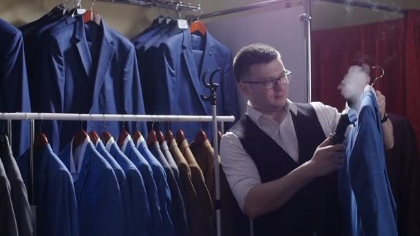 Продавець чоловіка в магазині костюмів знімає куртку, готуючи його до продажу . — стокове відео