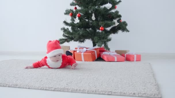 Schattige baby in het kostuum van de Kerstman, op zoek naar een geschenk — Stockvideo