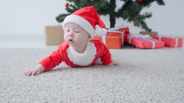 Schattige baby in het kostuum van de Kerstman, op zoek naar een geschenk — Stockvideo