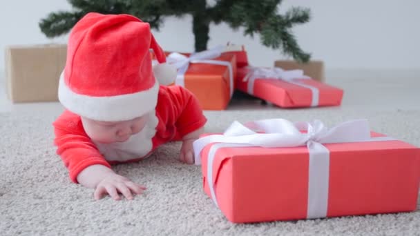 Söt baby i kostym av Santa Claus, tittar en gåva — Stockvideo