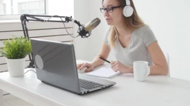 Akarsu ve yayın kavramını. Neşeli kız stüdyoda bir mikrofona konuşur