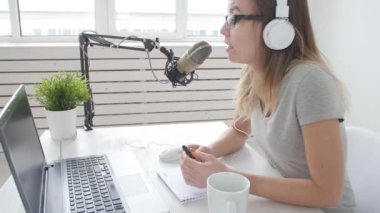 Akarsu ve yayın kavramını. Neşeli kız stüdyoda bir mikrofona konuşur