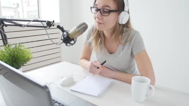 Concept of streaming and broadcasting. Young cheerful girl in the studio speaks into a microphone — Stock Video