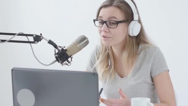 Concepto de streaming y radiodifusión. Joven chica alegre en el estudio habla en un micrófono — Vídeo de stock