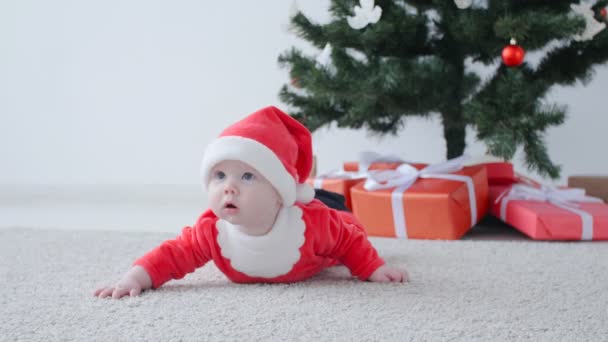 Χριστουγεννιάτικη ιδέα. Χαριτωμένο μωρό στο κοστούμι του Άγιου Βασίλη, ψάχνει ένα δώρο — Αρχείο Βίντεο