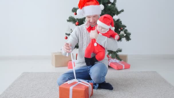 Vánoční koncepce. Roztomilé dítě na tatínky ruce v Santa Claus čepice. — Stock video