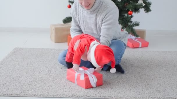 Χριστουγεννιάτικη ιδέα. Χαριτωμένο μωρό για μπαμπάδες χέρια σε Αϊ Βασίλη καπέλο. — Αρχείο Βίντεο