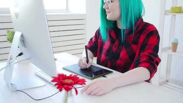 Jovem designer gráfico com cabelos coloridos trabalhando no computador usando tablet — Vídeo de Stock