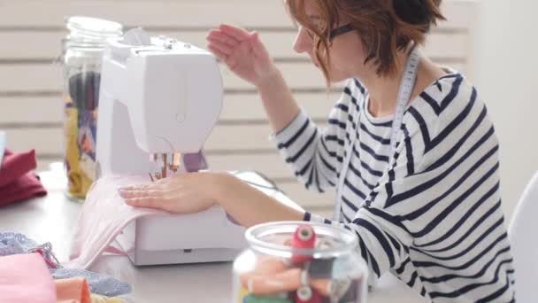 Concepto de pequeña empresa y pequeña producción. Joven bonita modista mujer cose ropa en el taller — Vídeos de Stock