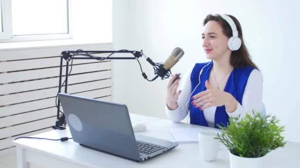Streaming- und Sendekonzept. junges fröhliches Mädchen im Studio spricht ins Mikrofon — Stockvideo