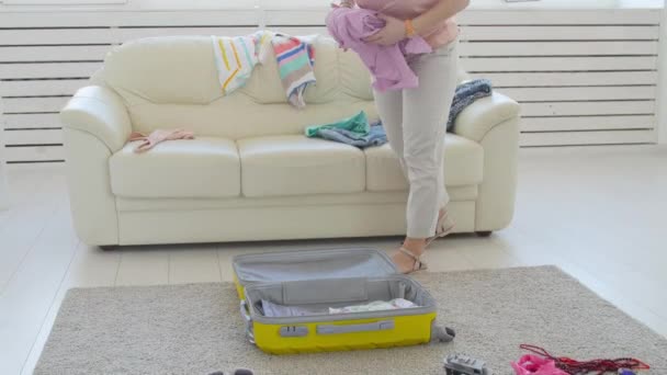 Travel and vacation concept. Young attractive woman puts clothes in a suitcase, going on vacation at home — Stock Video