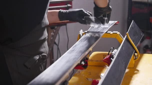 Skidunderhåll och reparations koncept. Verkstads arbetare gör vaxning och reparationer skidor och snowboard — Stockvideo