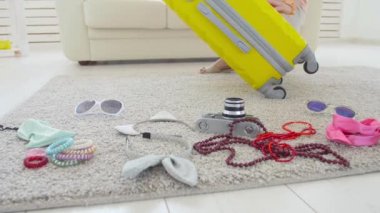 Seyahat ve tatil konsepti. Mutlu genç kadın yeni bir yolculuk için bavul içine renkli yazlık giysiler ambalaj