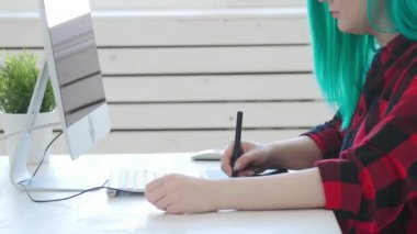 Serbest çalışma veya ofis çalışması kavramı. Ofiste veya evde çalışan renkli saçlı genç kadın grafik tasarımcı