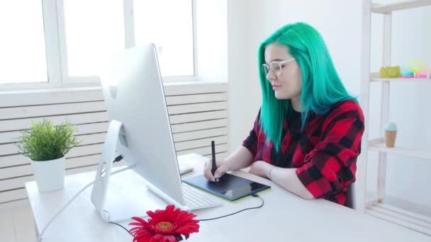 Conceito de trabalho freelancer ou de escritório. Jovem designer gráfico feminino com cabelos coloridos trabalhando no escritório ou em casa — Vídeo de Stock