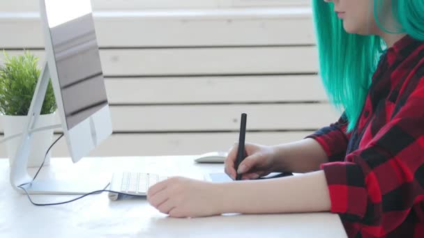 Concepto de trabajo autónomo o de oficina. Joven diseñadora gráfica femenina con cabello coloreado trabajando en la oficina o en casa — Vídeos de Stock