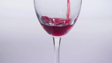 Yiyecek ve içecek kavramı. Kırmızı veya pembe şarap beyaz bir arka plan üzerinde bir bardağa dökülür.