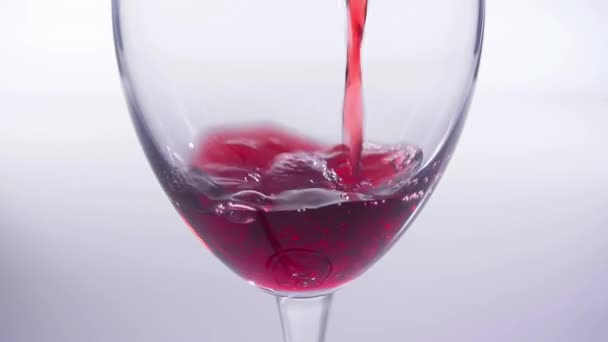 Η έννοια του φαγητού και των ποτών. Κόκκινο ή ροζ κρασί χύνεται σε ένα γυαλί σε λευκό φόντο. — Αρχείο Βίντεο
