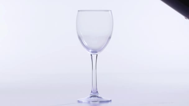 Konzept von Speisen und Getränken. Roter oder rosafarbener Wein, der in ein Glas auf weißem Hintergrund gegossen wird. — Stockvideo