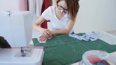 Hobi ve küçük işletme kavramı. Genç kadın tasarımcı parlak bir stüdyo atölyesinde giysi tasarlıyor