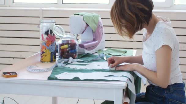 Hobi ve küçük işletme kavramı. Genç kadın tasarımcı parlak bir stüdyo atölyesinde giysi tasarlıyor — Stok video