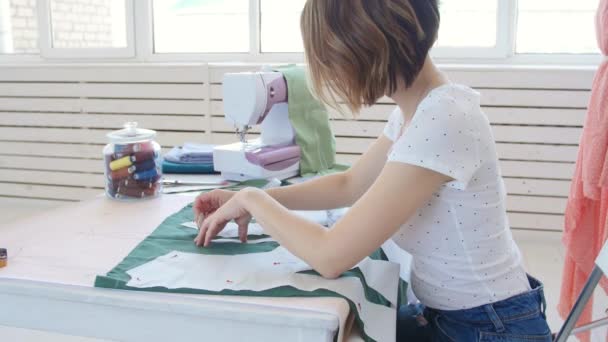 Concept of hobby and small business. Young female designer is designing clothes in a bright studio workshop — Stock Video