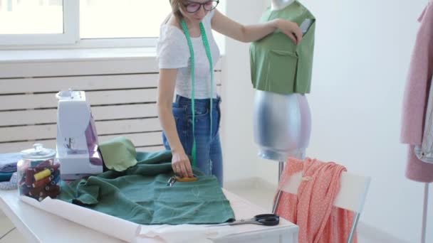 Η έννοια του χόμπι και των μικρών επιχειρήσεων. Νέα γυναίκα σχεδιαστής σχεδιάζει ρούχα σε ένα φωτεινό εργαστήρι στούντιο — Αρχείο Βίντεο
