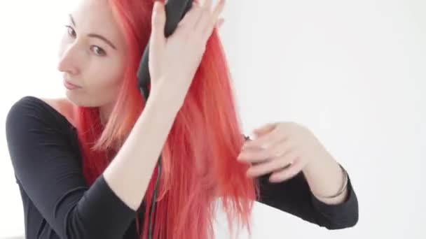 Hår-och frisör koncept. Ung kvinna med rött hår skapar en frisyr med ett strykjärn eller tång — Stockvideo