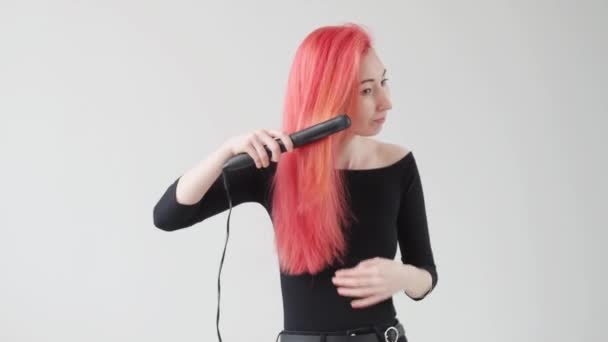 Concepto de pelo y peluquería. Mujer joven con el pelo rojo crea un peinado con una plancha o un tanga — Vídeos de Stock