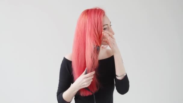 Concepto de pelo y peluquería. Mujer joven con el pelo rojo crea un peinado con una plancha o un tanga — Vídeos de Stock